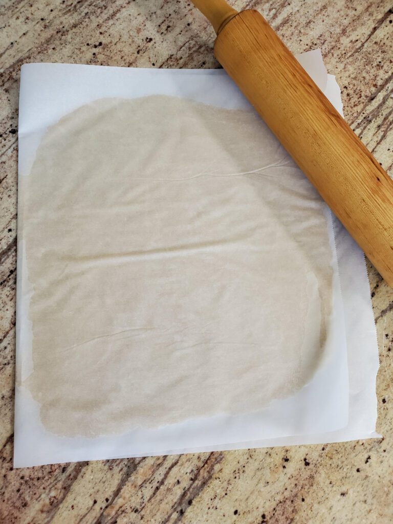 pie crust rolled out between 2 pieces of parchment paper