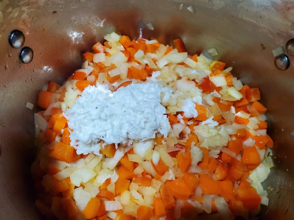 Adding coconut and garlic to sauteed vegetables.