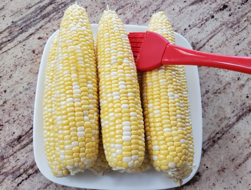 brushing butter on corn